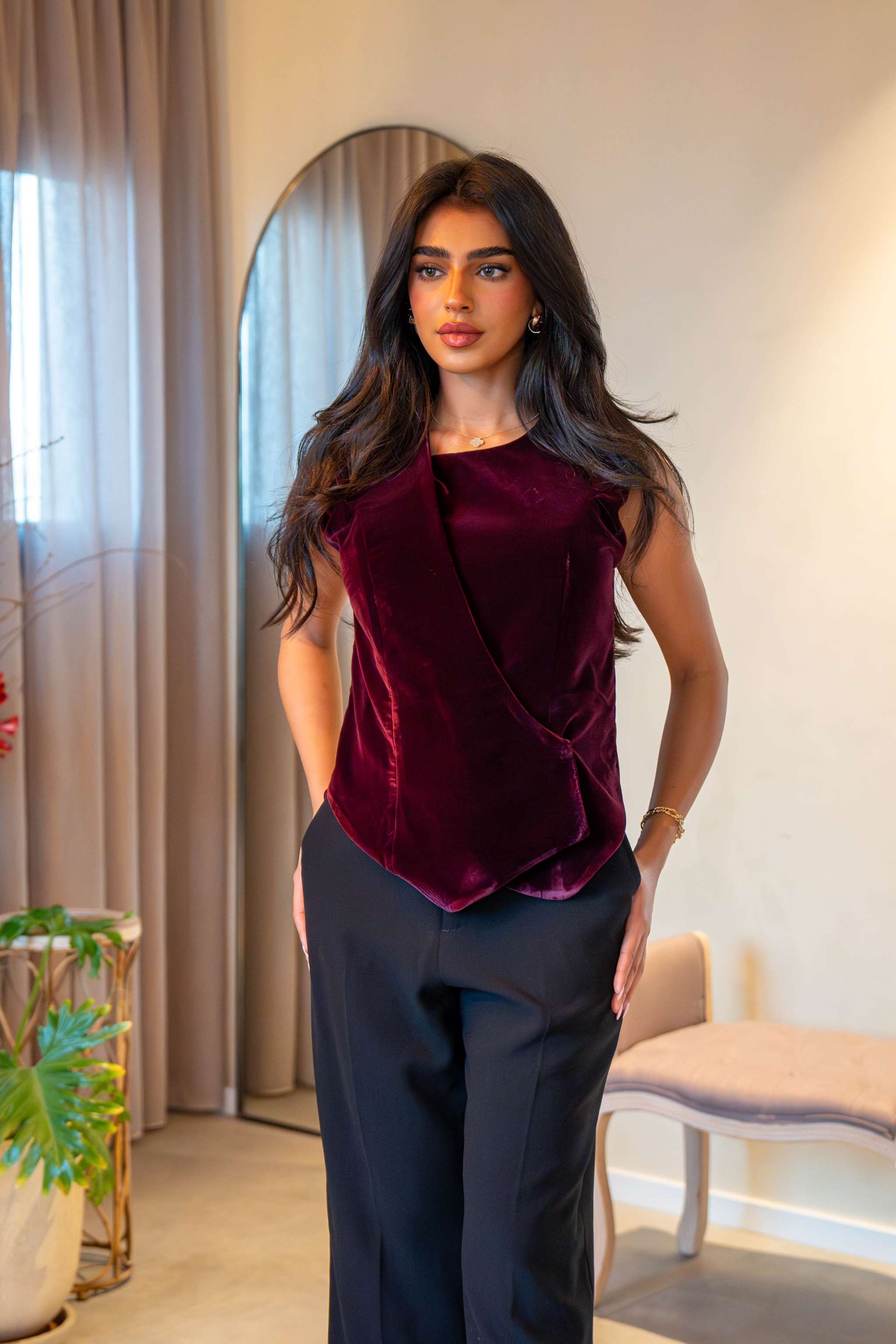 Woman wearing elegant maroon velvet vest with tailored fit paired with black pants indoors