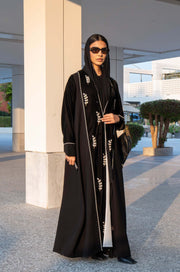Elegant black Veloura Abaya with gold embroidery and velvet accents, perfect for special occasions.