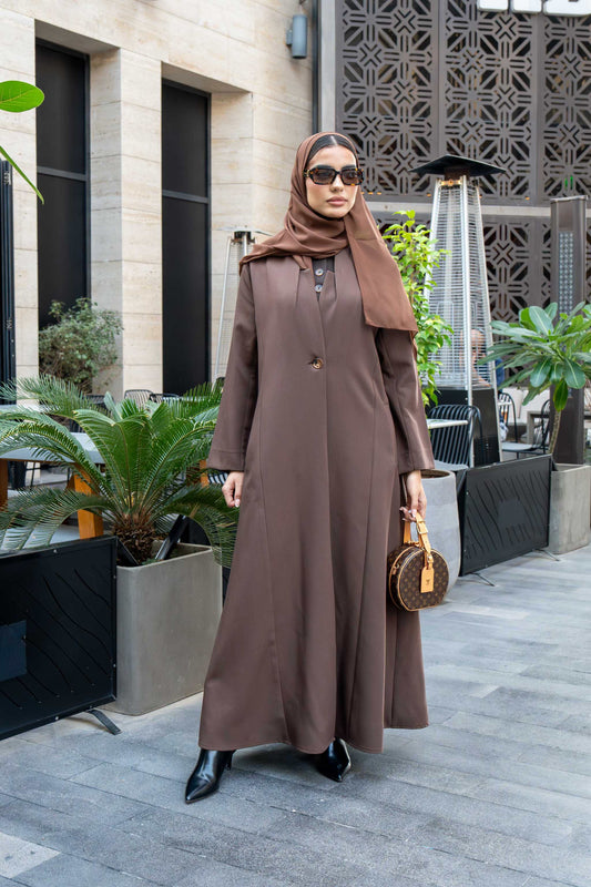 woman wearing classic brown crepe abaya with hijab and sunglasses outdoors carrying a small handbag