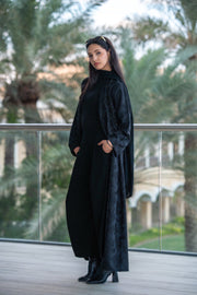 woman wearing elegant black abaya with textured patterned panels and structured sleeves outdoors