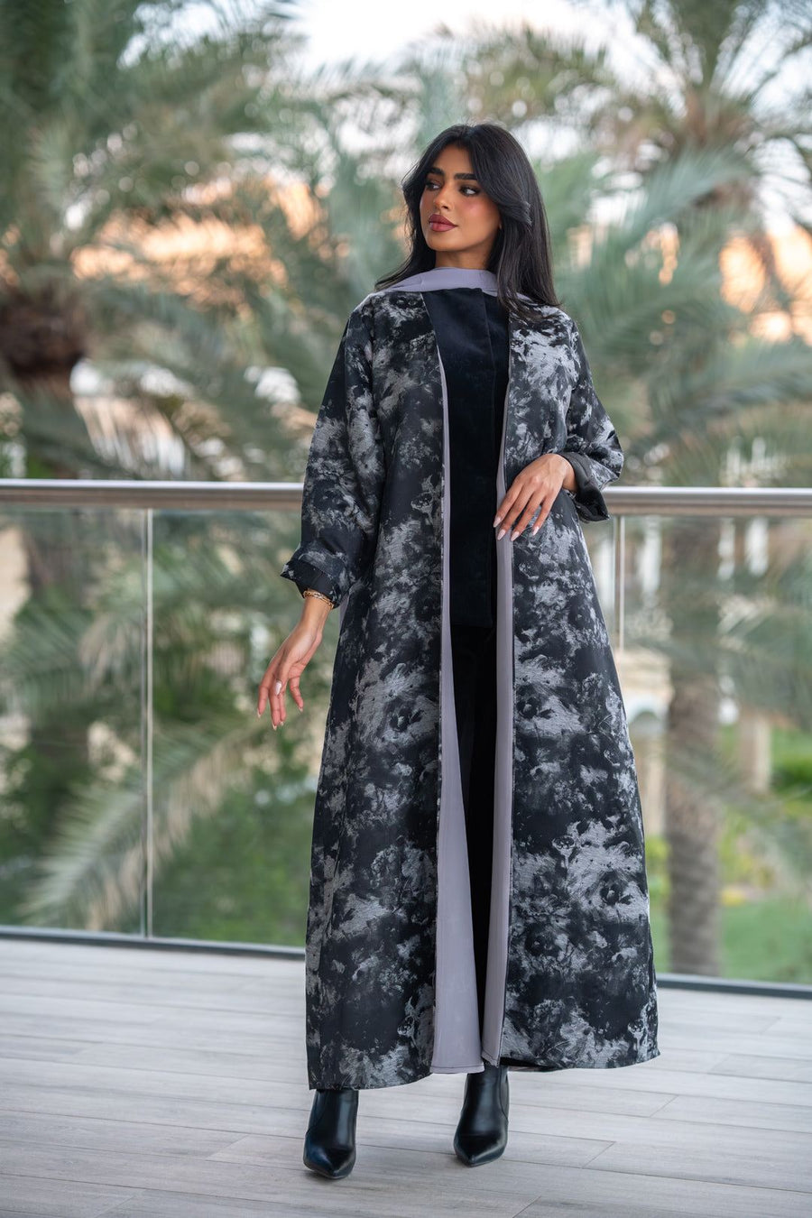 Woman wearing a black and gray jacquard abaya with textured weave and soft chiffon lining, standing outdoors.