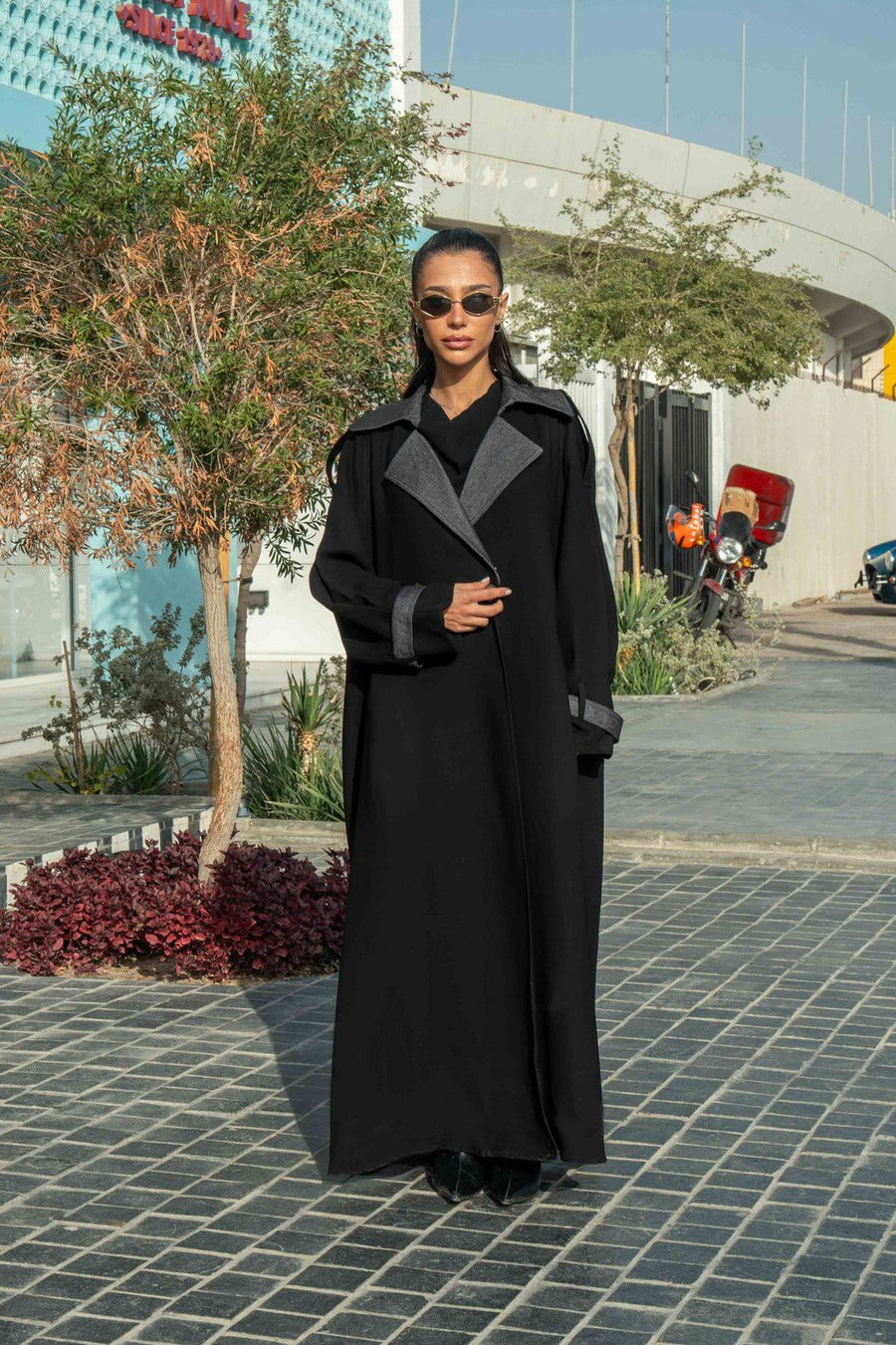 Woman wearing black crepe abaya with grey lapels and cuffs in urban outdoor setting