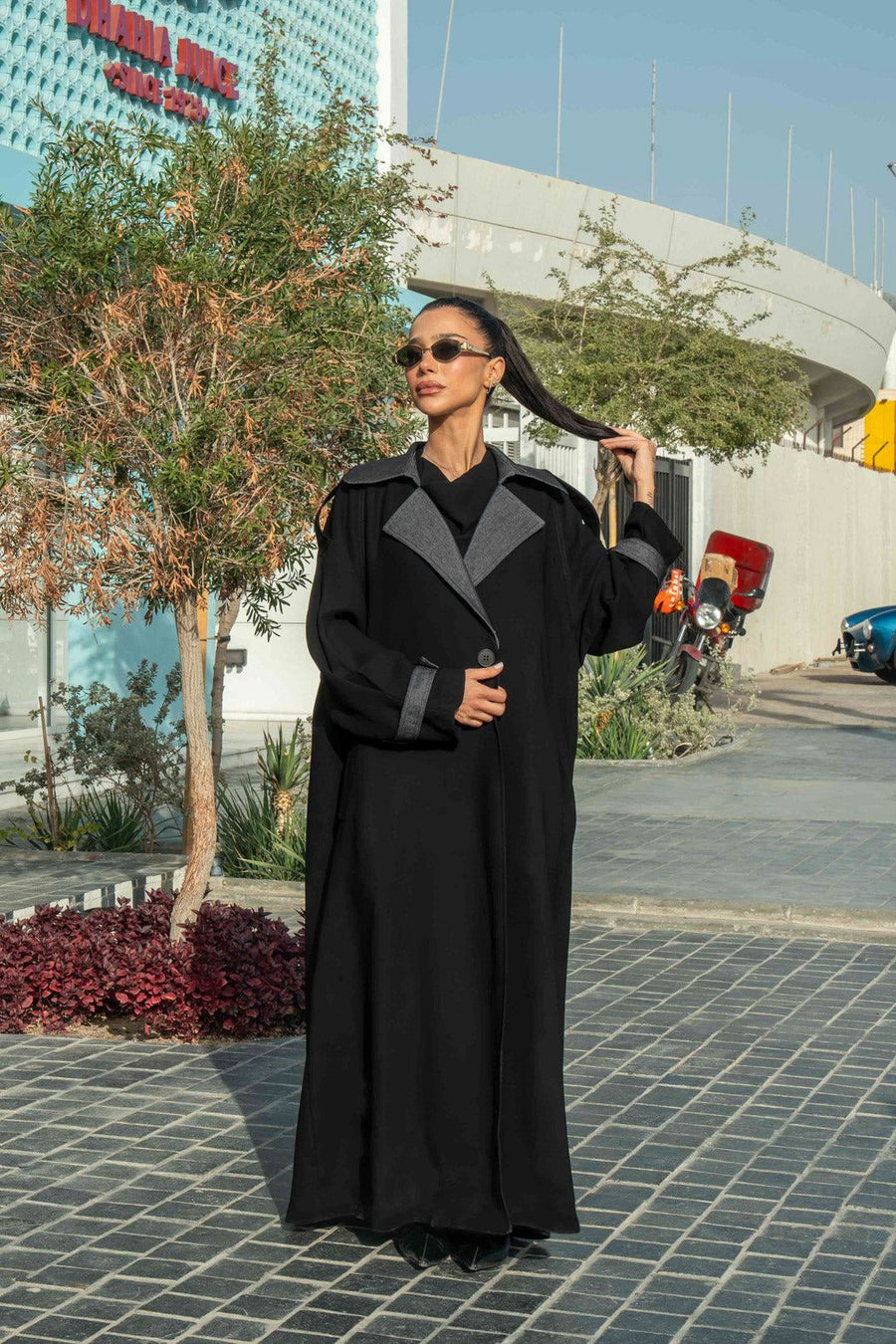 Woman wearing black crepe abaya with grey lapels and cuffs in urban outdoor setting