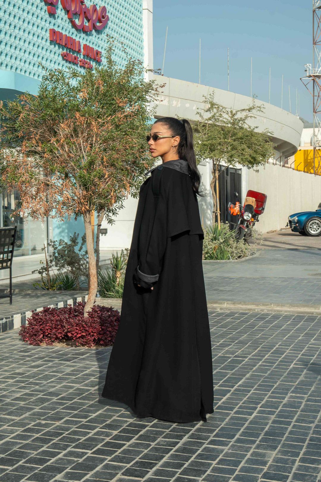 Woman wearing black crepe abaya with grey lapels and cuffs in urban outdoor setting