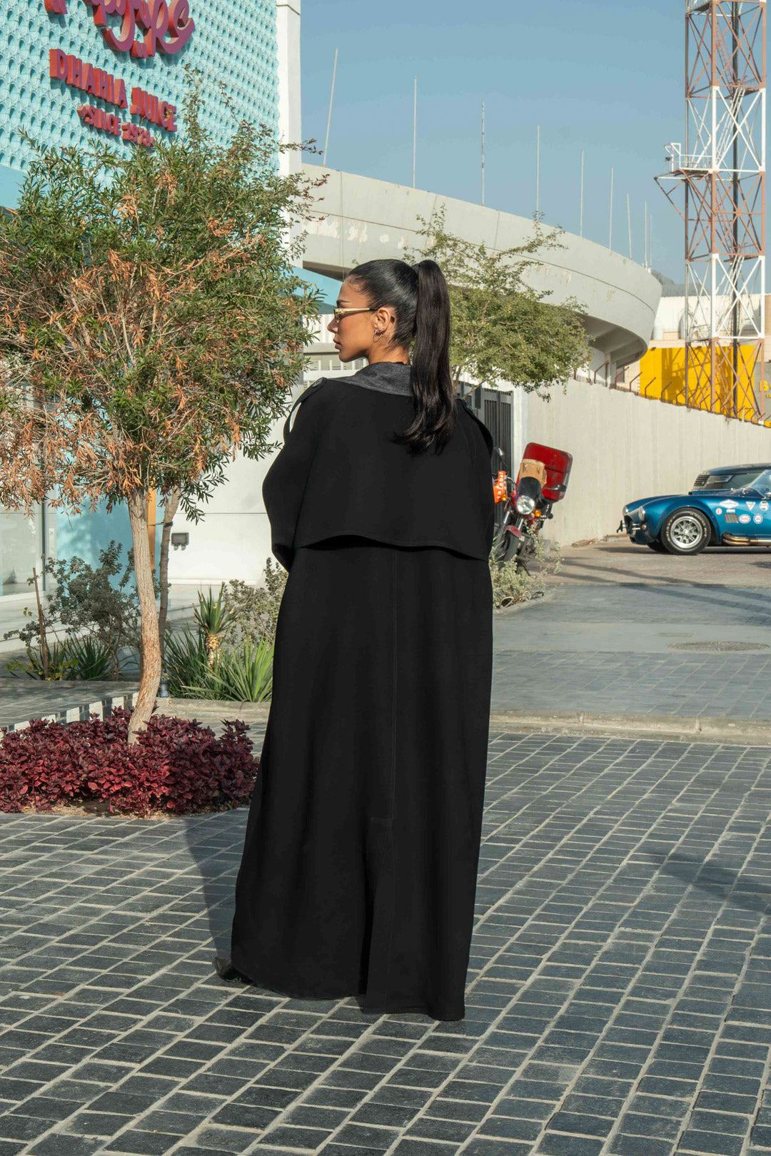 Woman wearing black crepe abaya with grey lapels and cuffs in urban outdoor setting