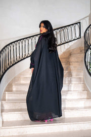 Black dress with magenta panels and butterfly-style embroidered neckline paired with matching black bisht with contrast piping