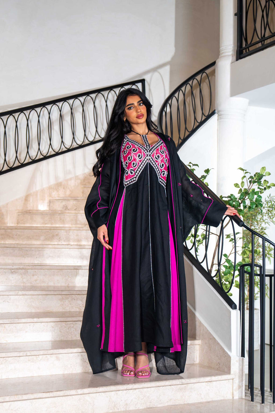 Black dress with magenta panels and butterfly-style embroidered neckline paired with matching black bisht with contrast piping
