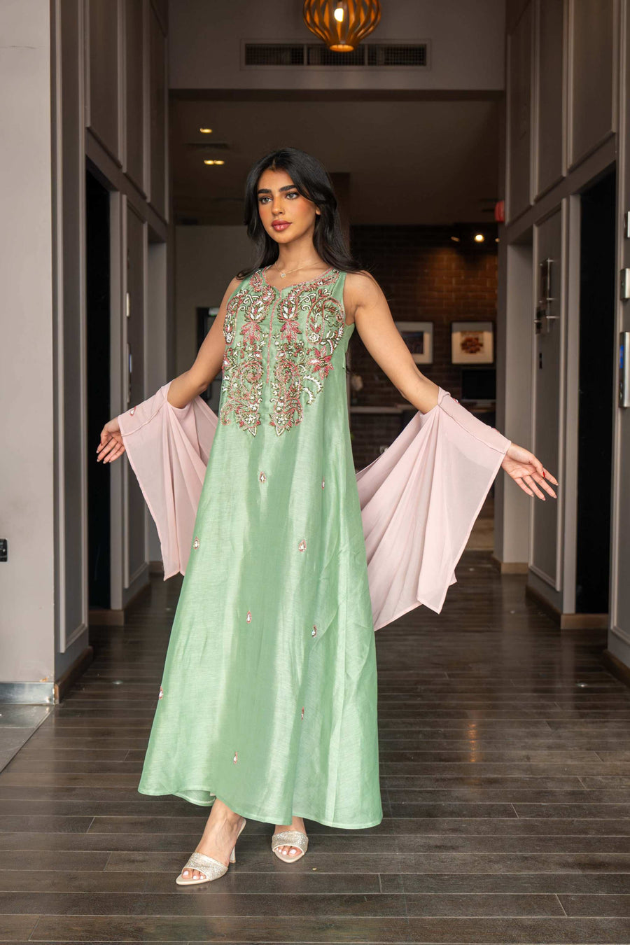 Soft pastel green one-piece dress with floral embroidery and flowing blush pink cape sleeves for spring and summer.