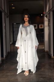 Woman wearing a refined white dress with blue embroidered neckline and soft asymmetric bisht with minimal embroidery