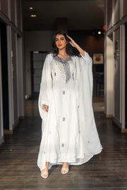 Woman wearing a refined white dress with blue embroidered neckline and soft asymmetric bisht with minimal embroidery