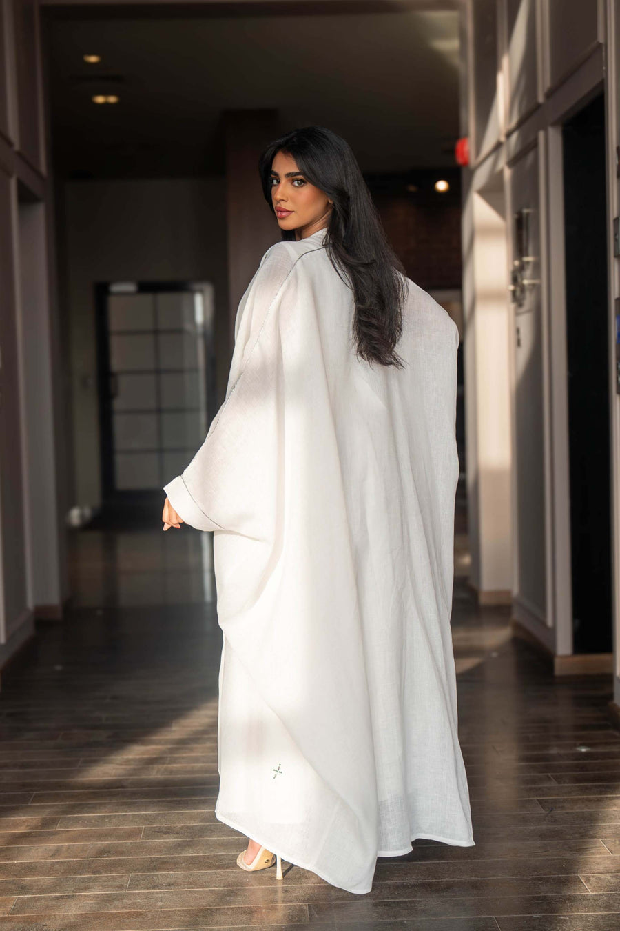 Woman wearing a refined white dress with blue embroidered neckline and soft asymmetric bisht with minimal embroidery