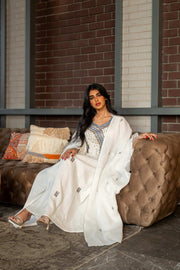 Woman wearing a refined white dress with blue embroidered neckline and soft asymmetric bisht with minimal embroidery