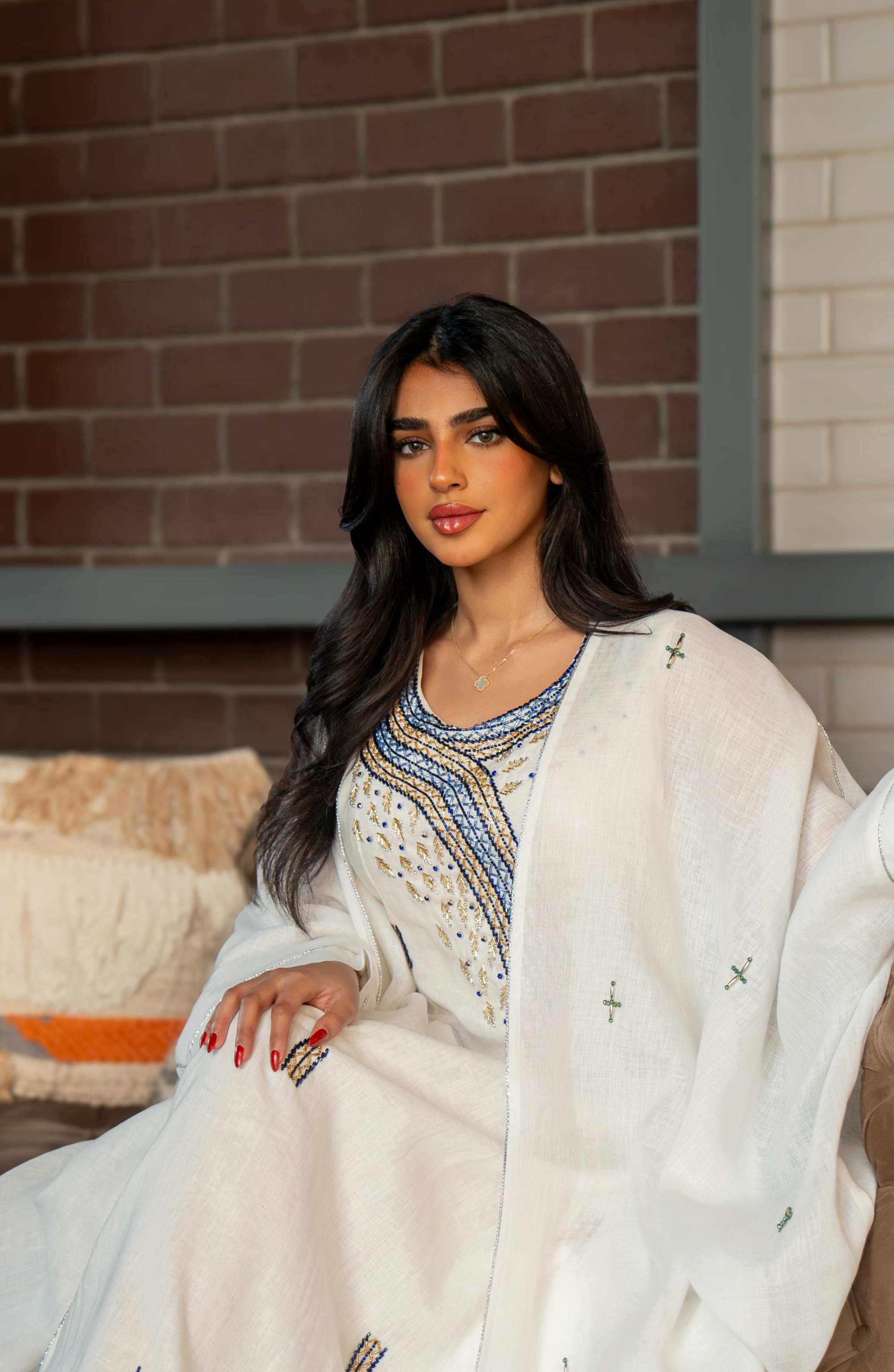 Woman wearing a refined white dress with blue embroidered neckline and soft asymmetric bisht with minimal embroidery