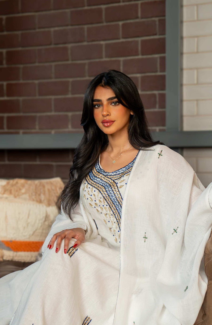 Woman wearing a refined white dress with blue embroidered neckline and soft asymmetric bisht with minimal embroidery