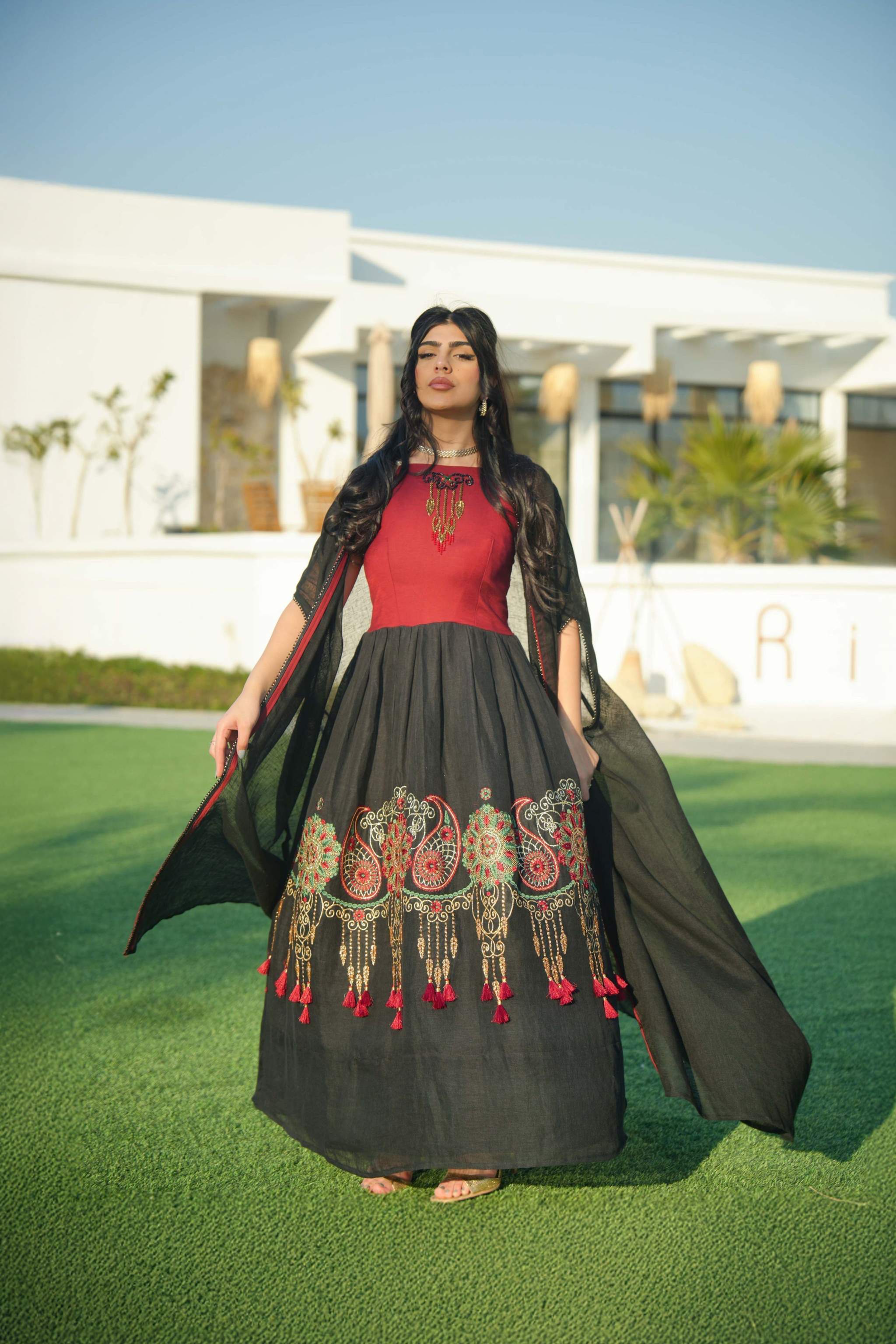 Woman wearing black and red embroidered khesha fabric dress with bold red detailing and lightweight texture outdoors
