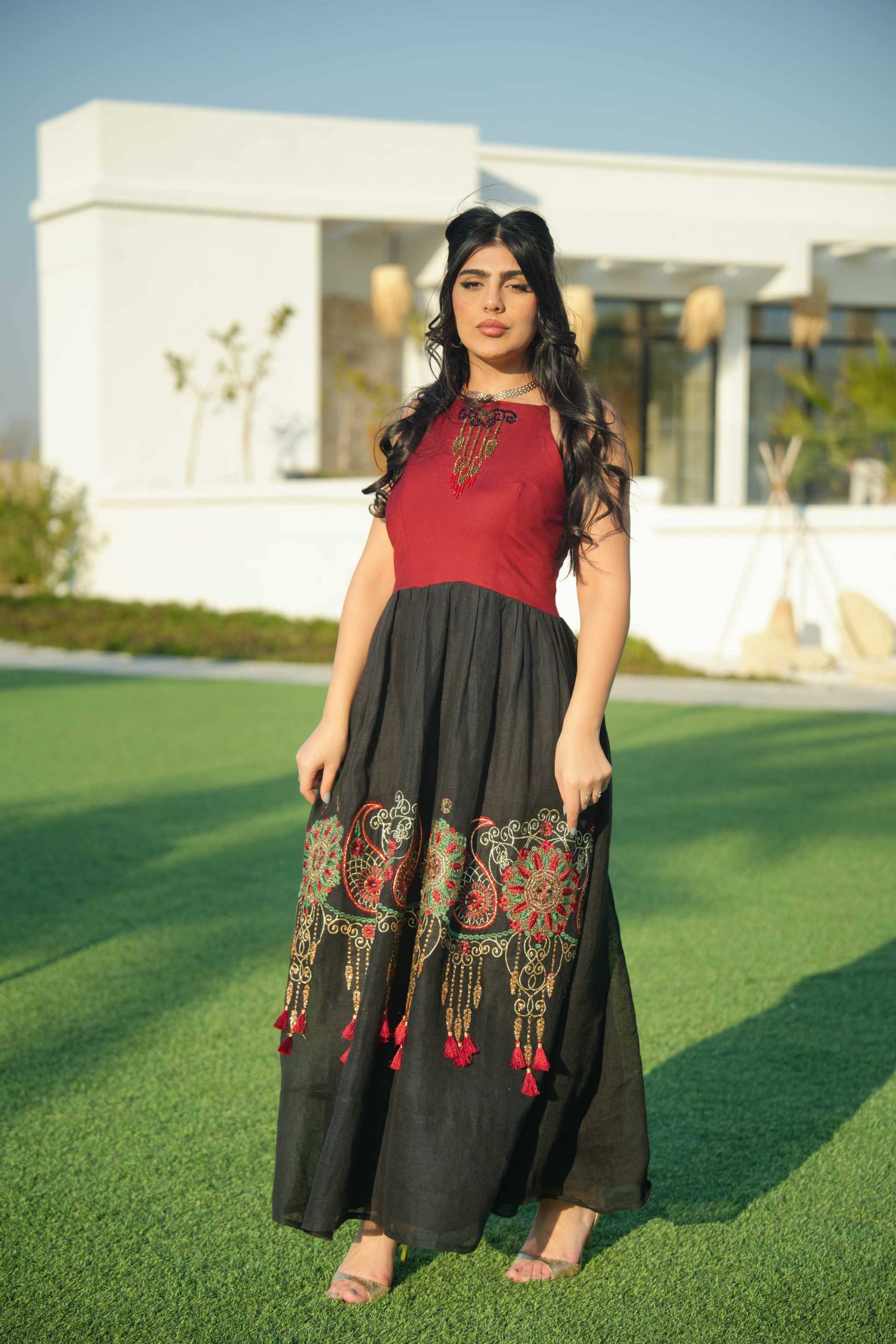 Woman wearing black and red embroidered khesha fabric dress with bold red detailing and lightweight texture outdoors