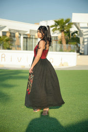 Woman wearing black and red embroidered khesha fabric dress with bold red detailing and lightweight texture outdoors