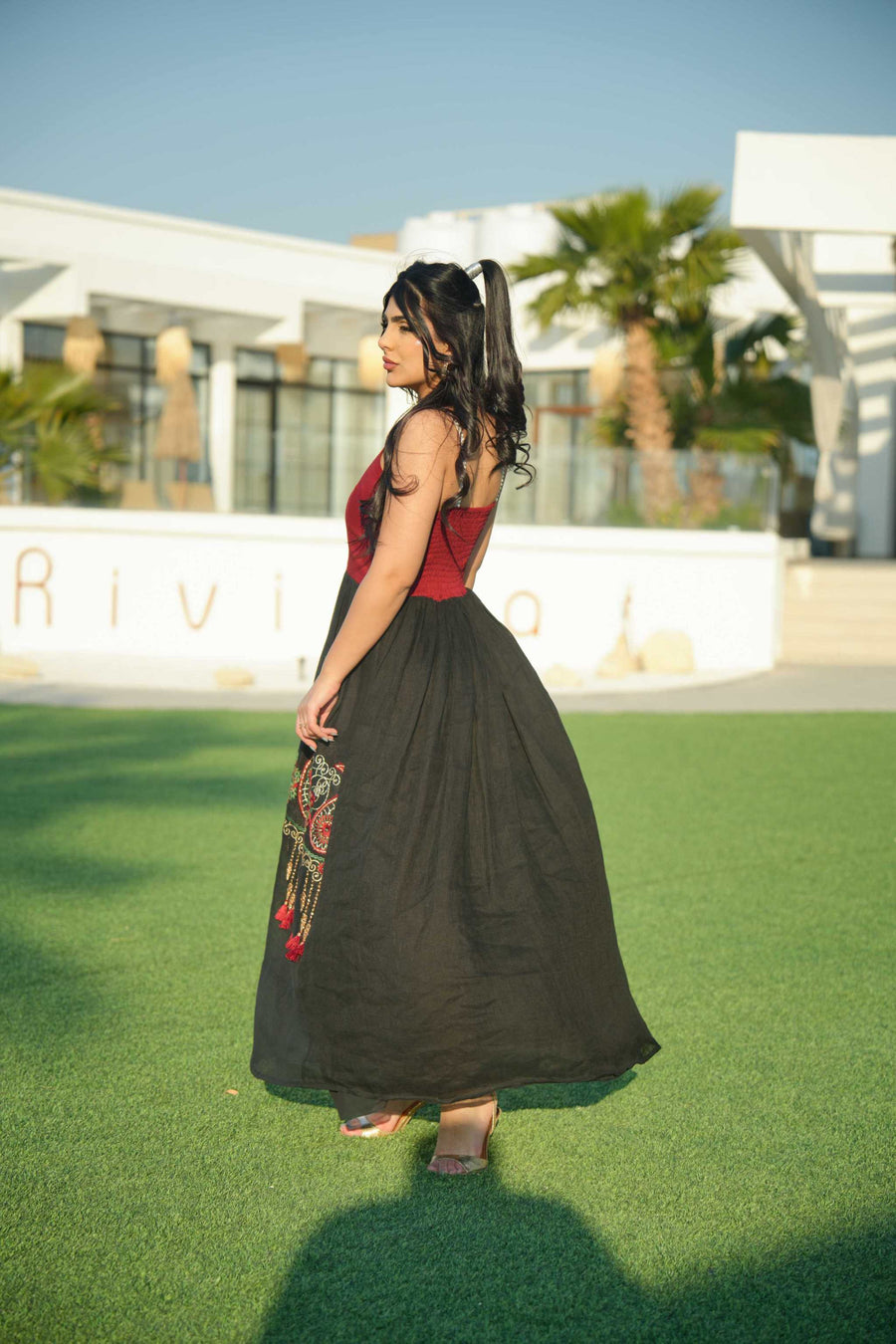 Woman wearing black and red embroidered khesha fabric dress with bold red detailing and lightweight texture outdoors