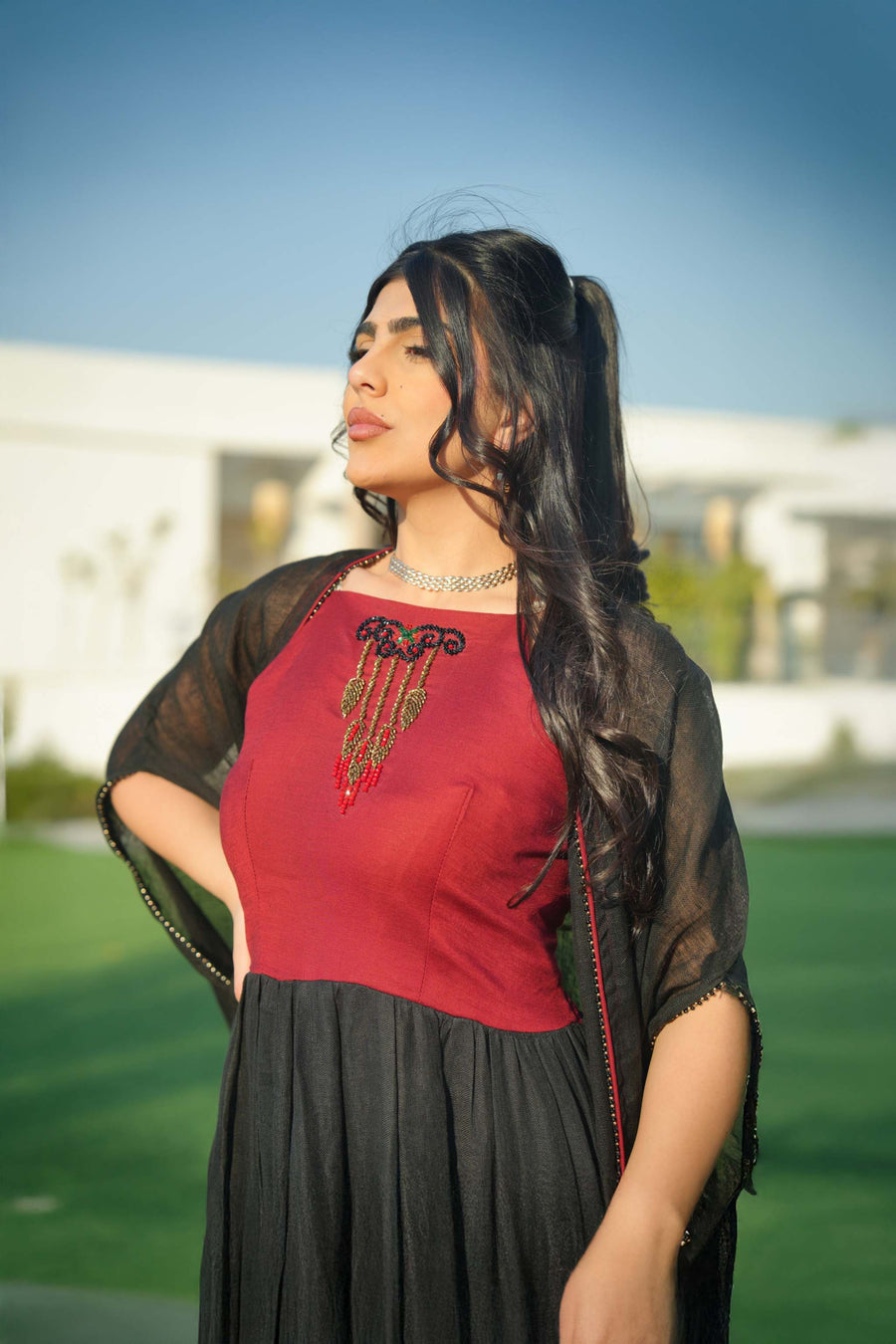 Woman wearing black and red embroidered khesha fabric dress with bold red detailing and lightweight texture outdoors