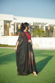 Woman wearing black and red embroidered khesha fabric dress with bold red detailing and lightweight texture outdoors