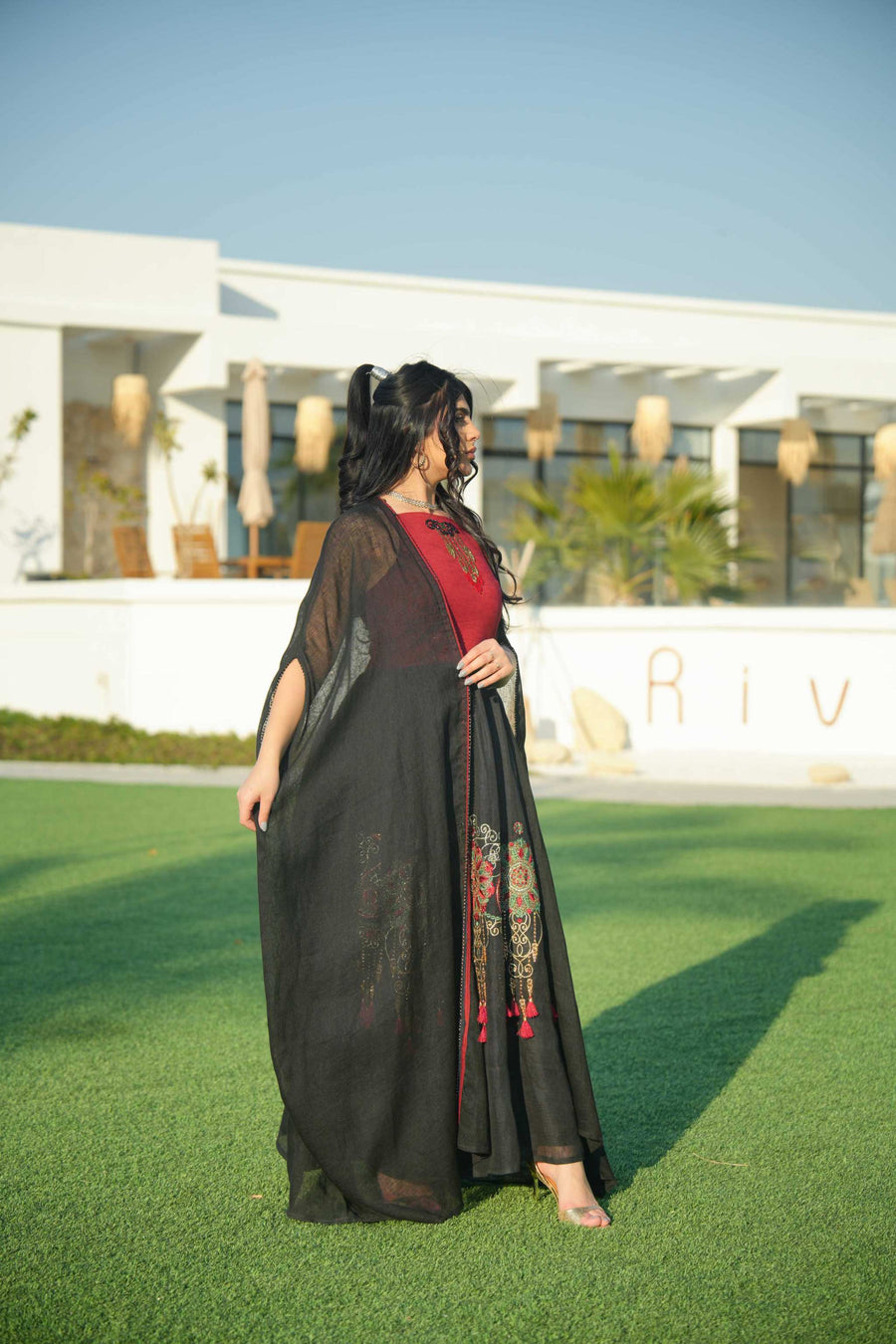 Woman wearing black and red embroidered khesha fabric dress with bold red detailing and lightweight texture outdoors