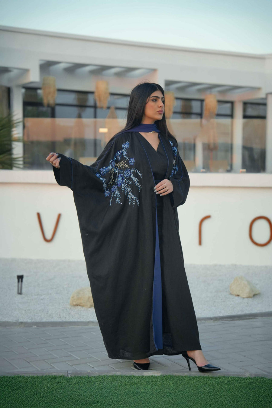luxurious black bisht with blue embroidery and mirrored details worn by woman outdoors