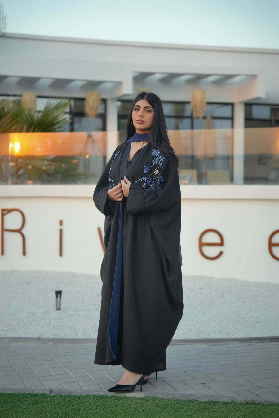 luxurious black bisht with blue embroidery and mirrored details worn by woman outdoors