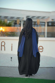luxurious black bisht with blue embroidery and mirrored details worn by woman outdoors