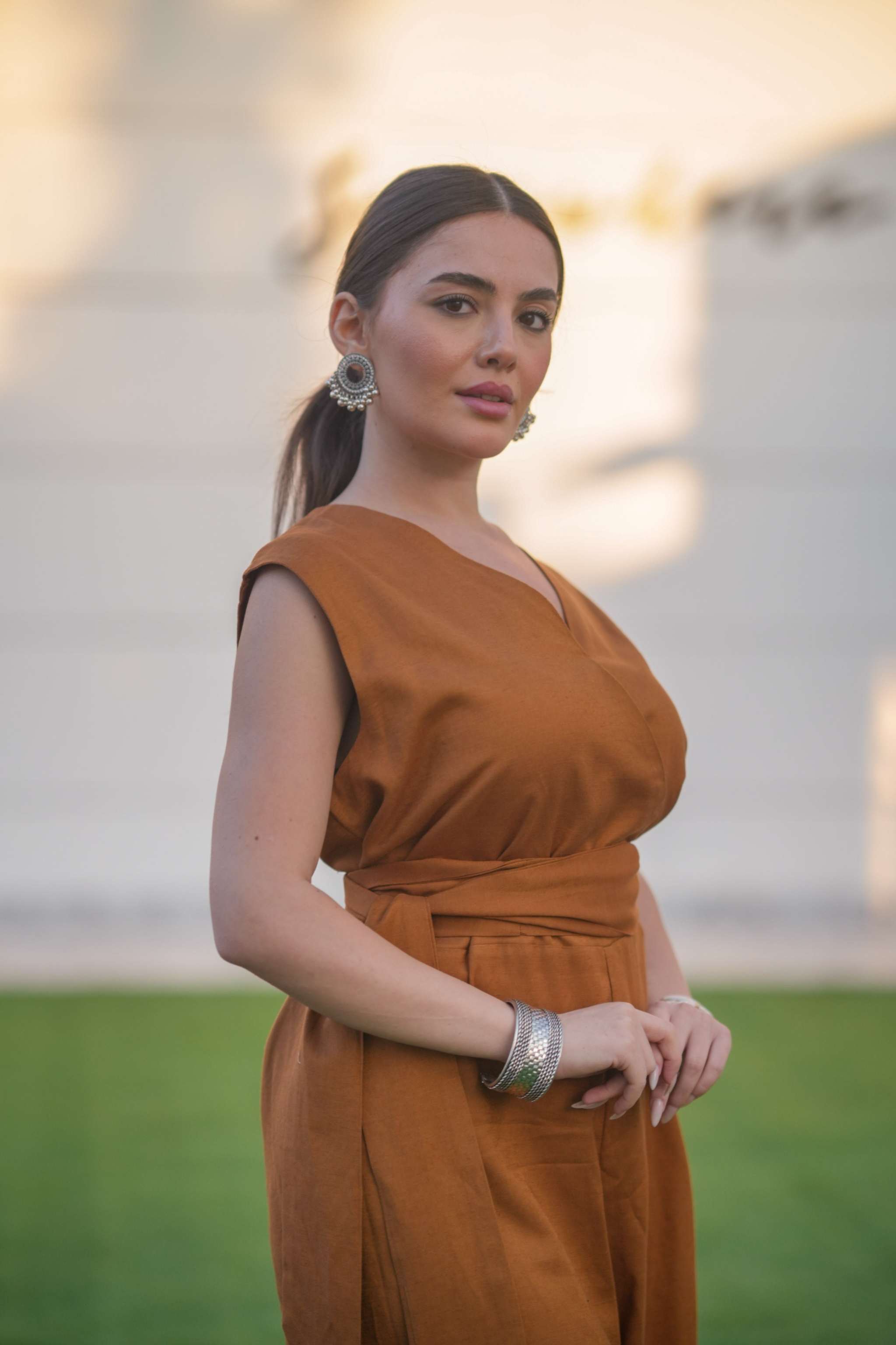 Woman wearing a tailored linen brown jumpsuit with defined waist and wide-leg silhouette outdoors
