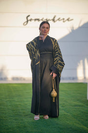 Black linen bisht with gold leaf embroidery, wide sleeves, and open front, styled for elegant eveningwear.