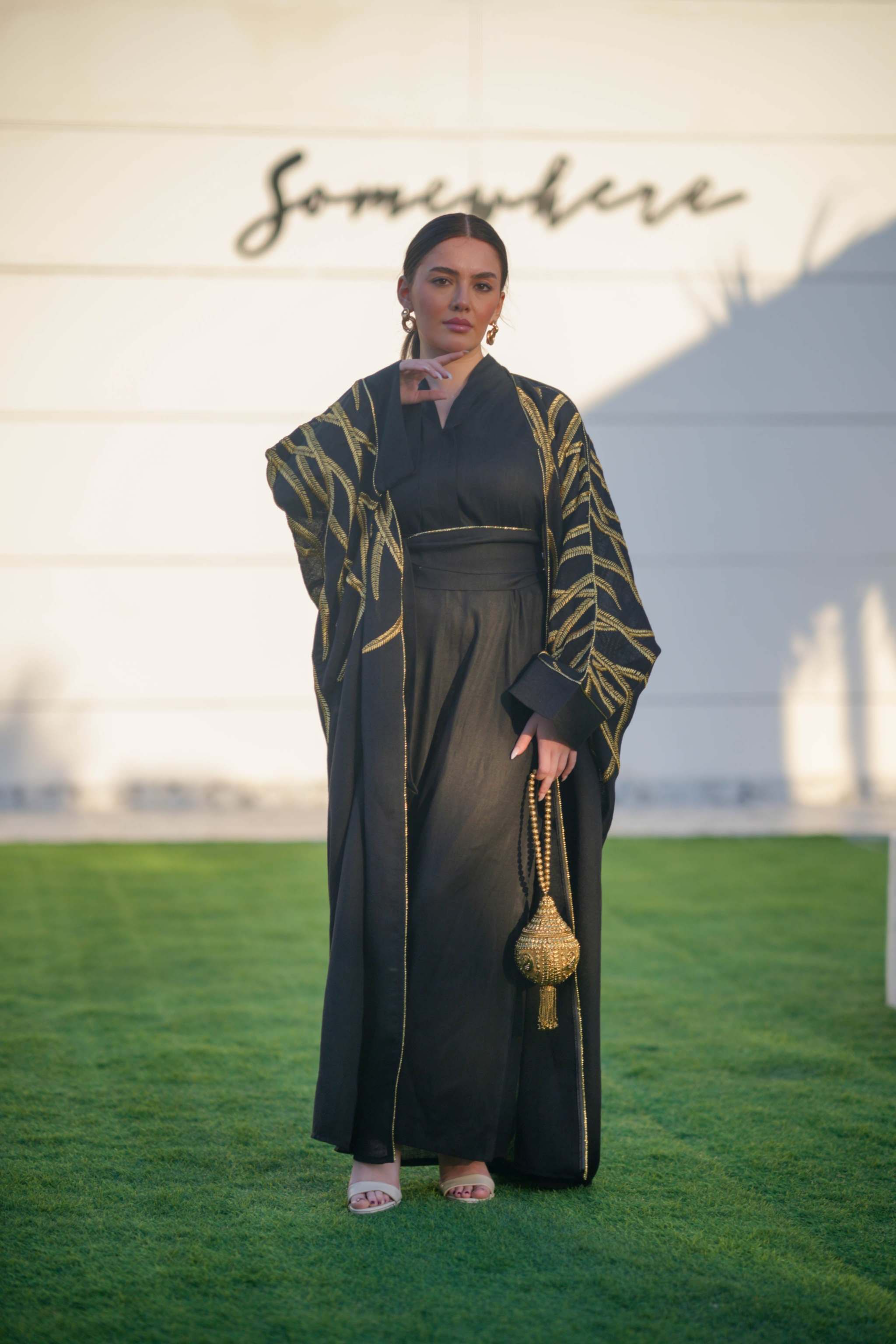 Black linen bisht with gold leaf embroidery, wide sleeves, and open front, styled for elegant eveningwear.