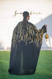 Black linen bisht with bold gold leaf embroidery, wide sleeves, and relaxed open front for elegant layering.