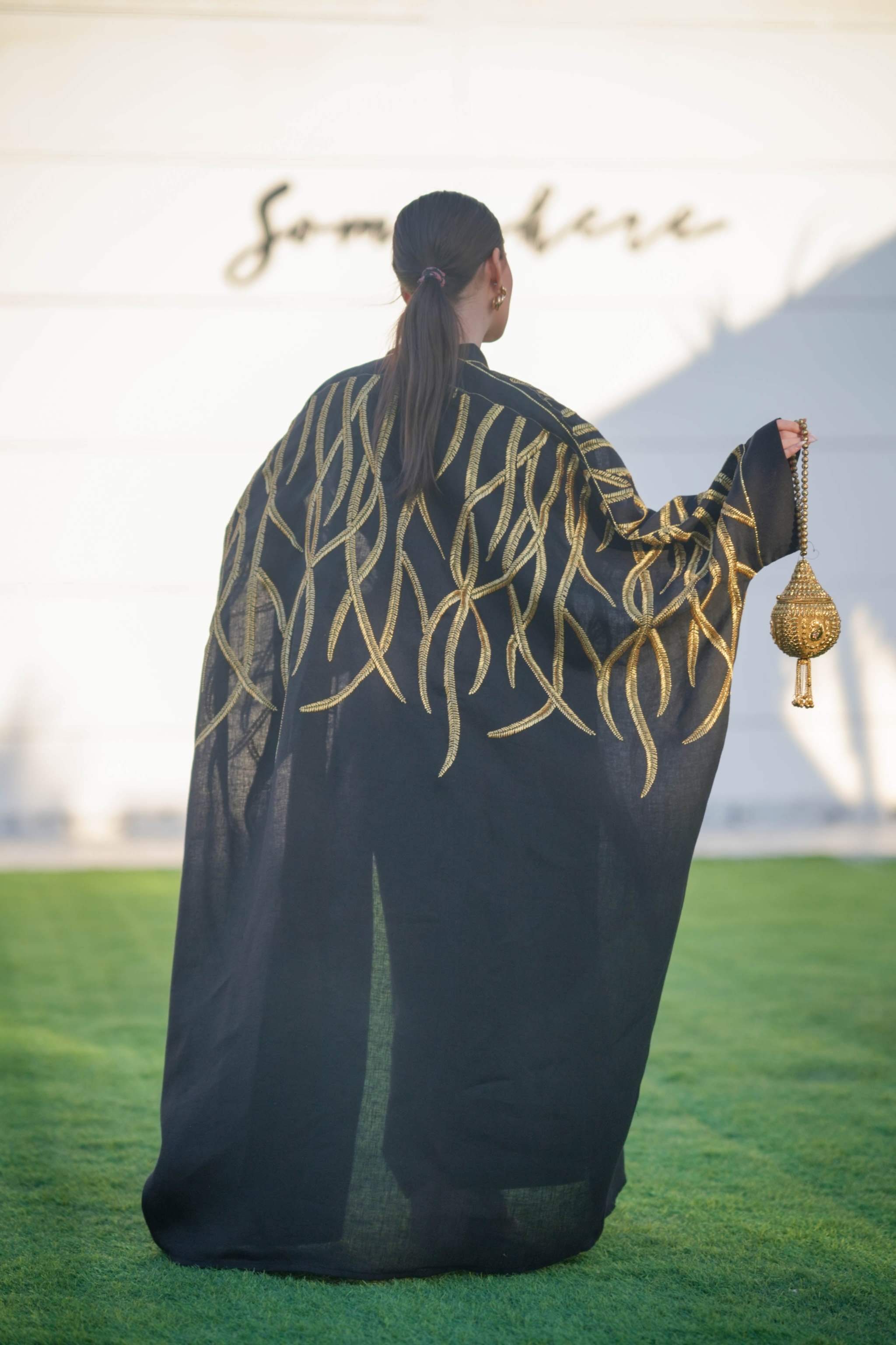Black linen bisht with bold gold leaf embroidery, wide sleeves, and relaxed open front for elegant layering.