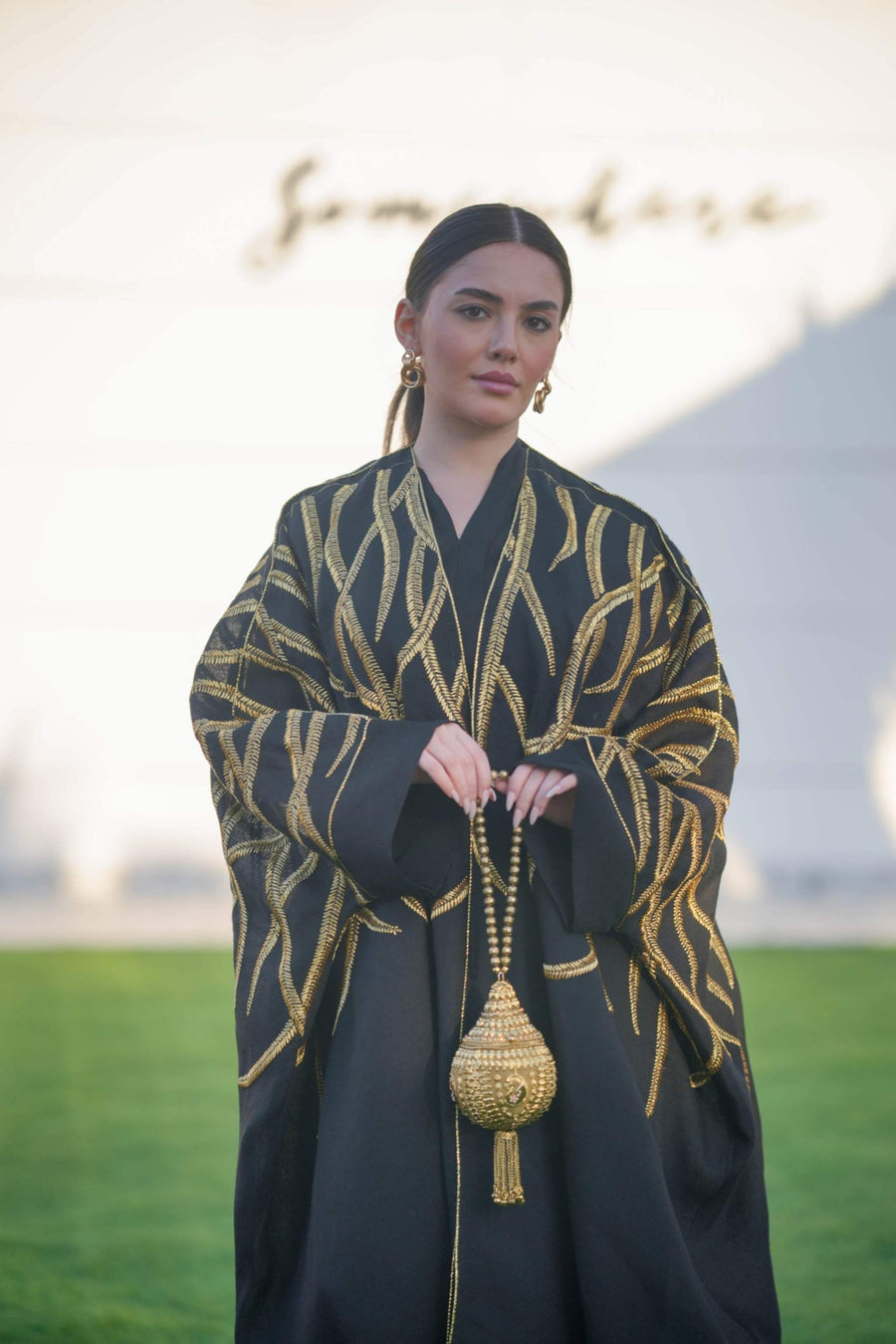 Black linen bisht with wide sleeves and bold gold leaf embroidery, styled for elegant layering and special occasions.