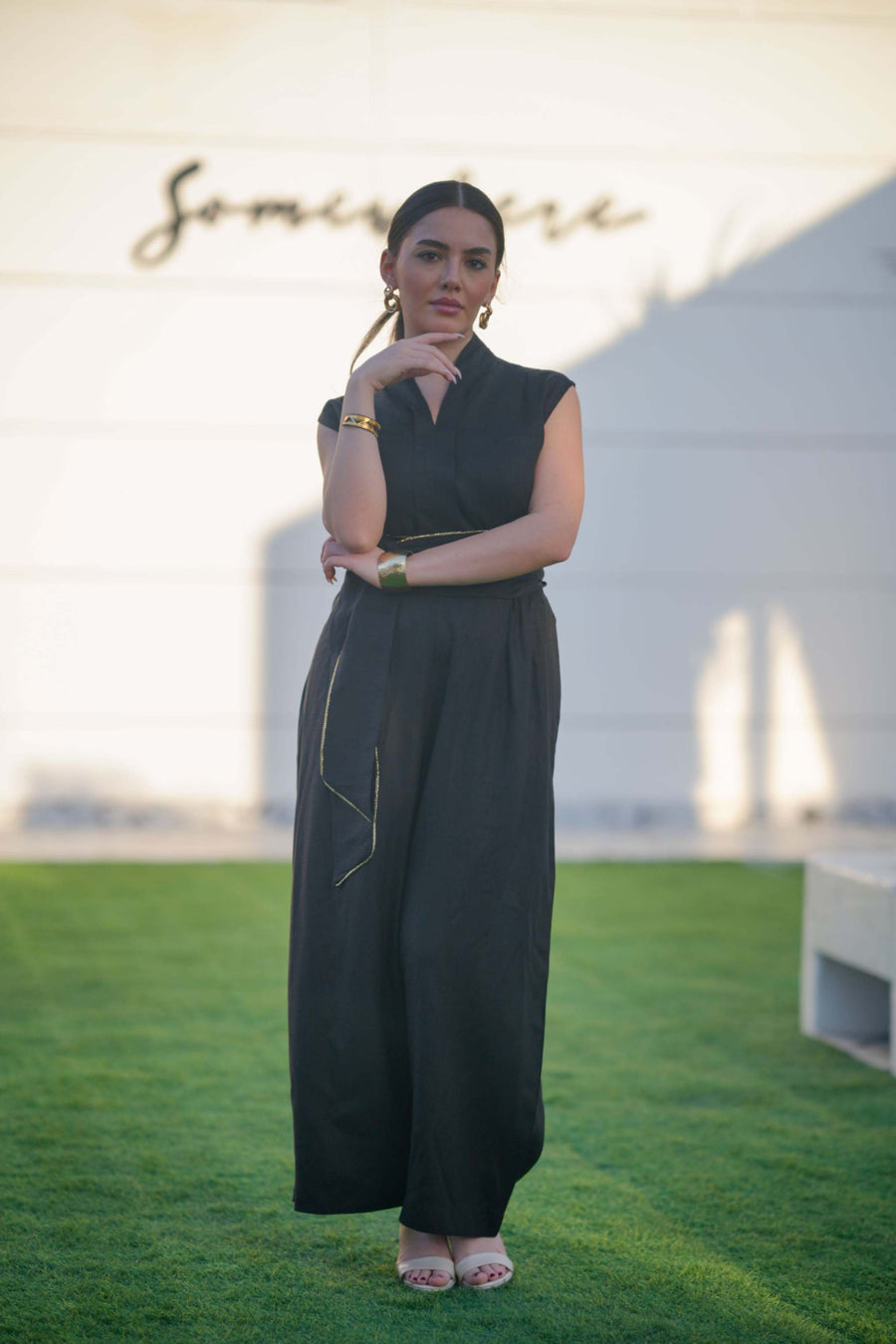 Woman wearing a sleek black linen jumpsuit with cinched waist and wide-leg cut standing on grass outdoors
