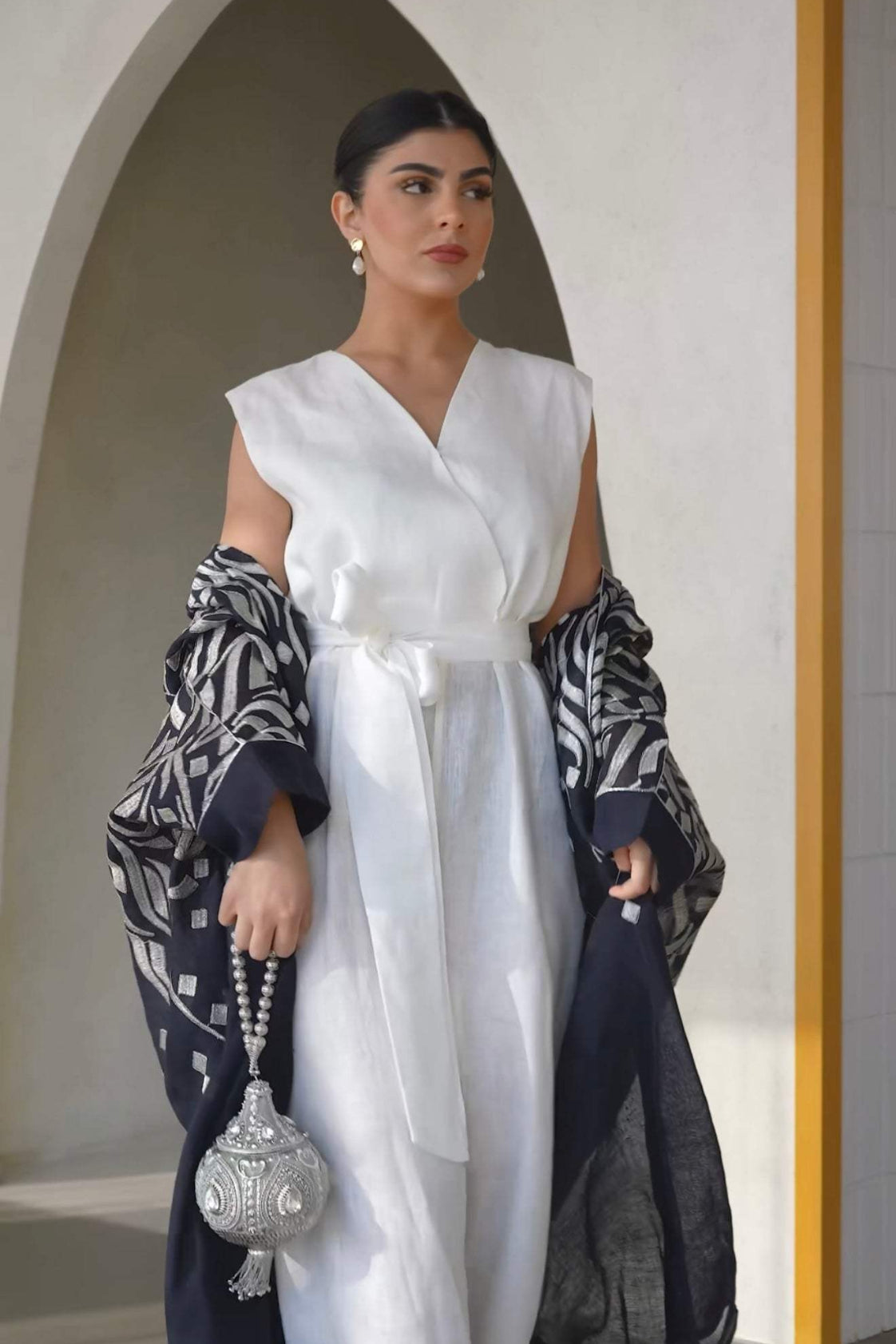 navy blue bisht with silver abstract embroidery on shoulders and sleeves worn over white outfit