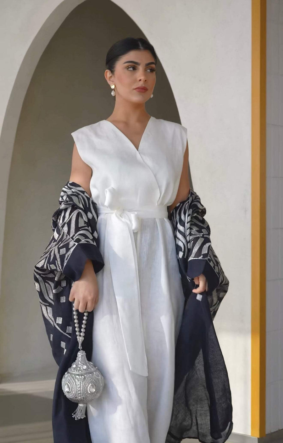 navy blue bisht with silver abstract embroidery on shoulders and sleeves worn over white outfit