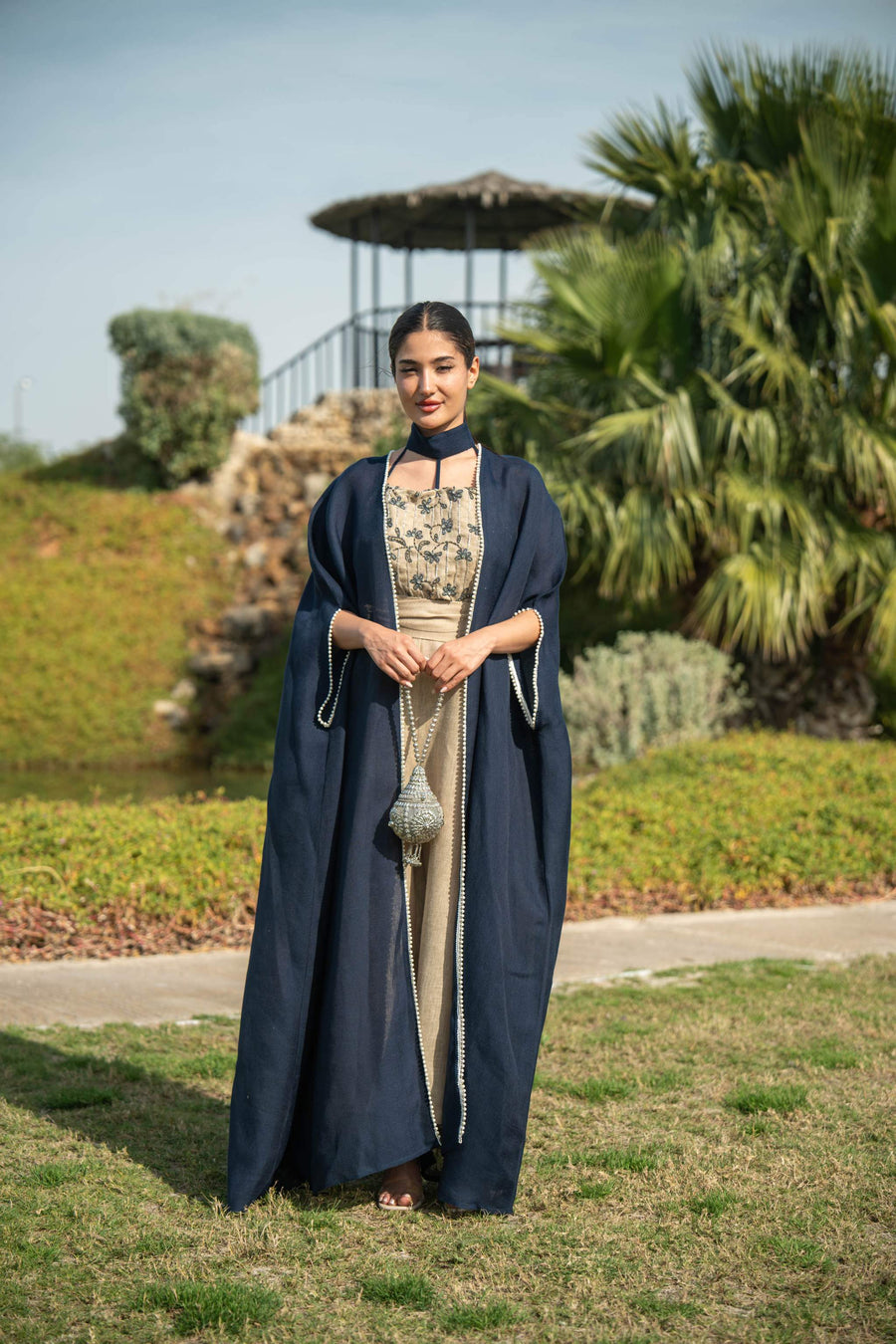 Elegant navy blue bisht with beige lining and delicate piping worn outdoors