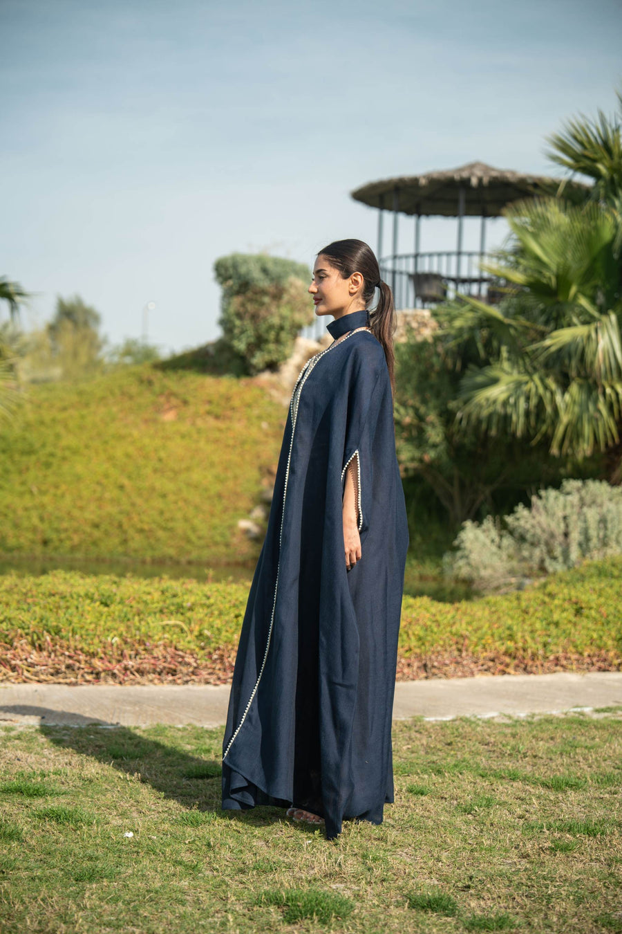 Elegant navy blue bisht with beige lining and delicate piping, featuring a flowing silhouette for day and evening wear.
