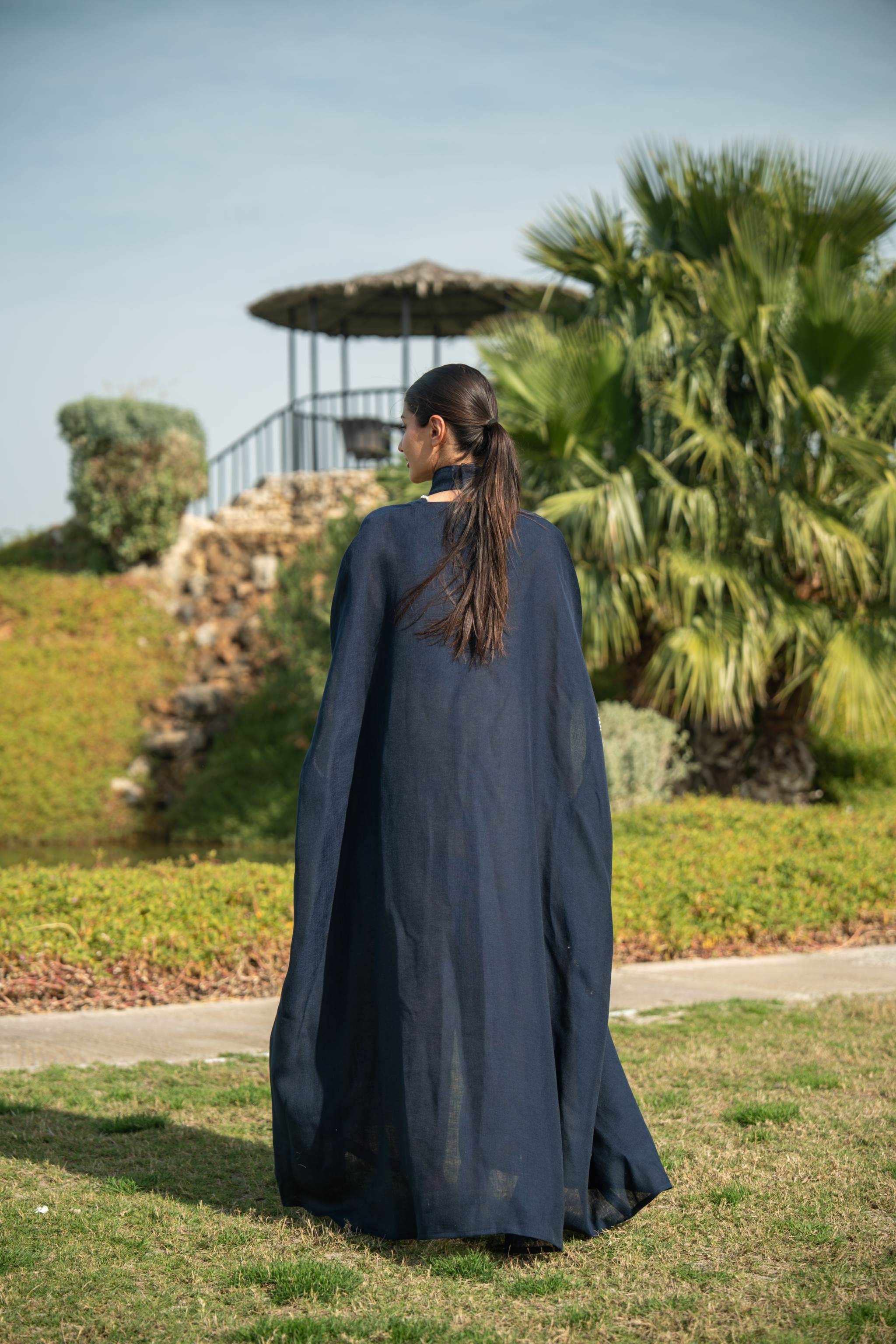 Elegant navy blue bisht with beige lining and delicate piping worn outdoors