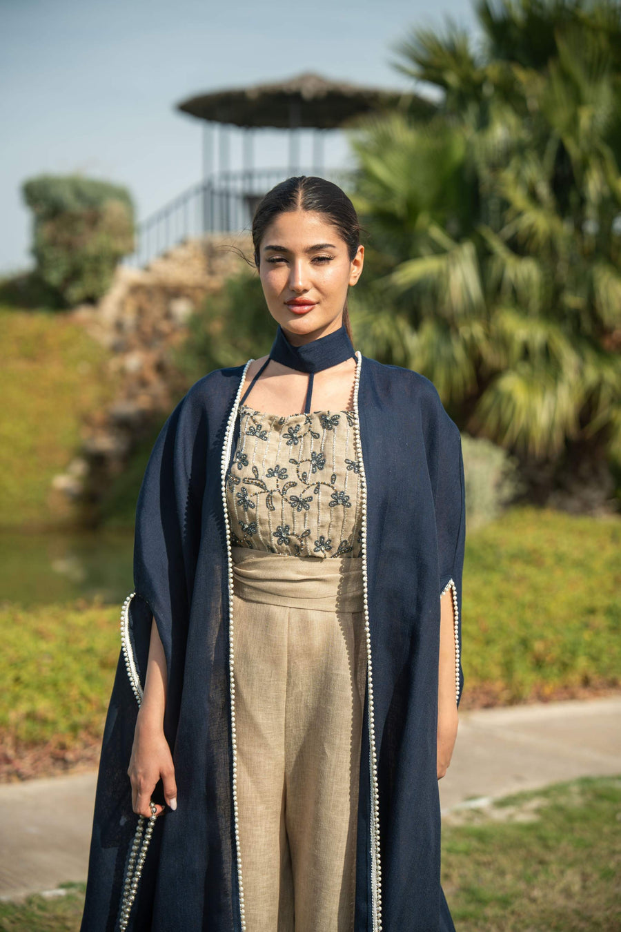 Elegant navy blue bisht with beige lining and delicate piping, worn as a flowing outer layer for day or evening occasions