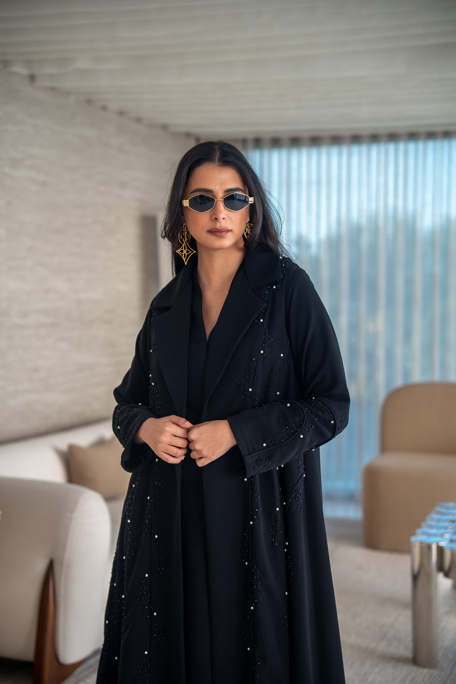 Velira black crepe abaya with delicate dot pattern embroidery and flowing silhouette worn by woman indoors