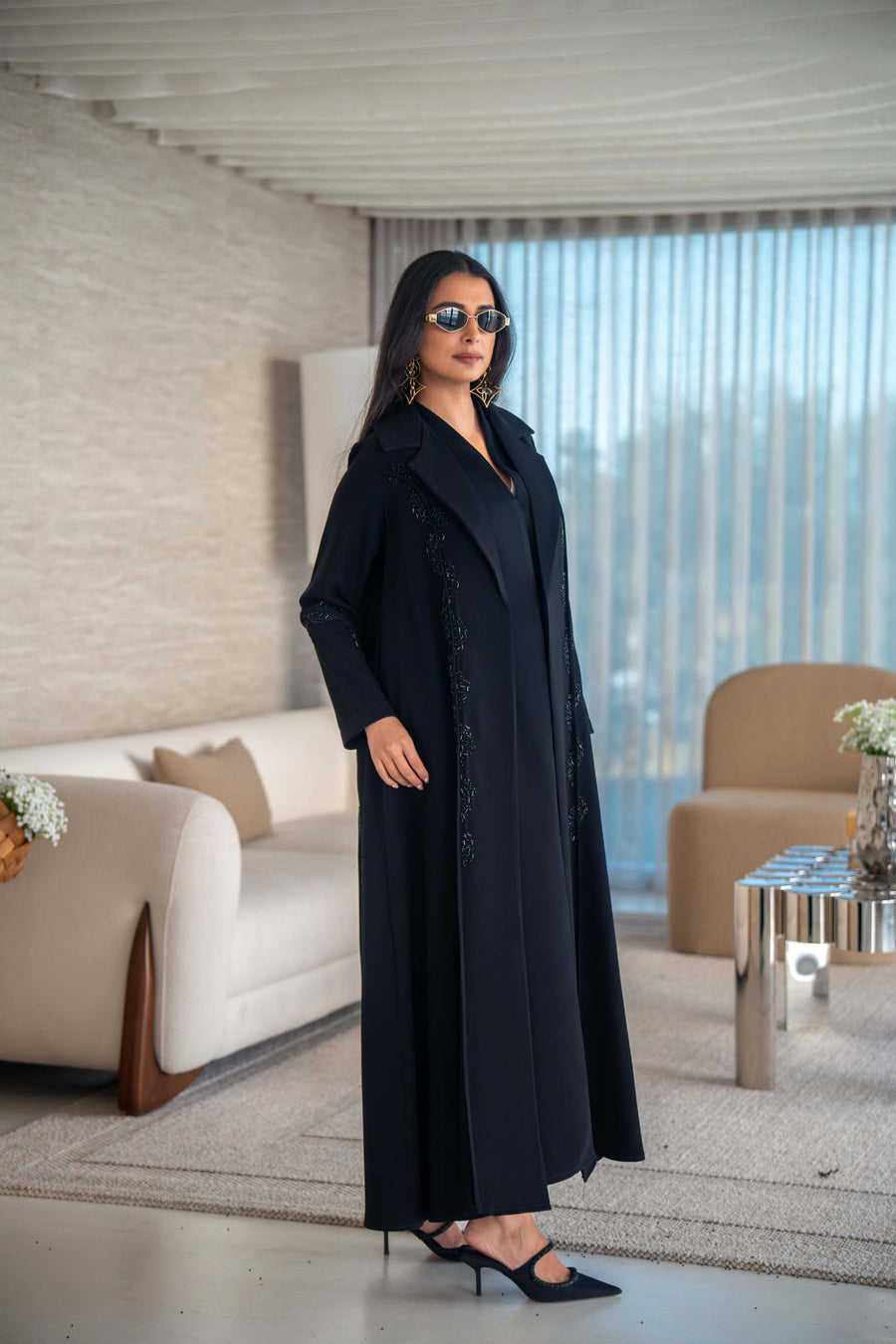 Woman wearing black flowing crepe abaya with sunglasses indoors