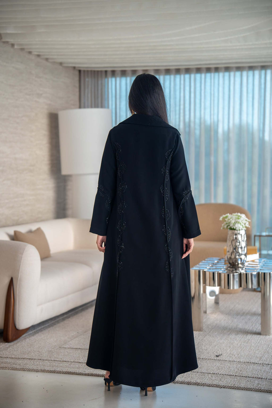 Woman wearing elegant black crepe abaya with flowing silhouette indoors