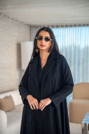woman wearing elegant black crepe abaya with flowing silhouette and sunglasses indoors