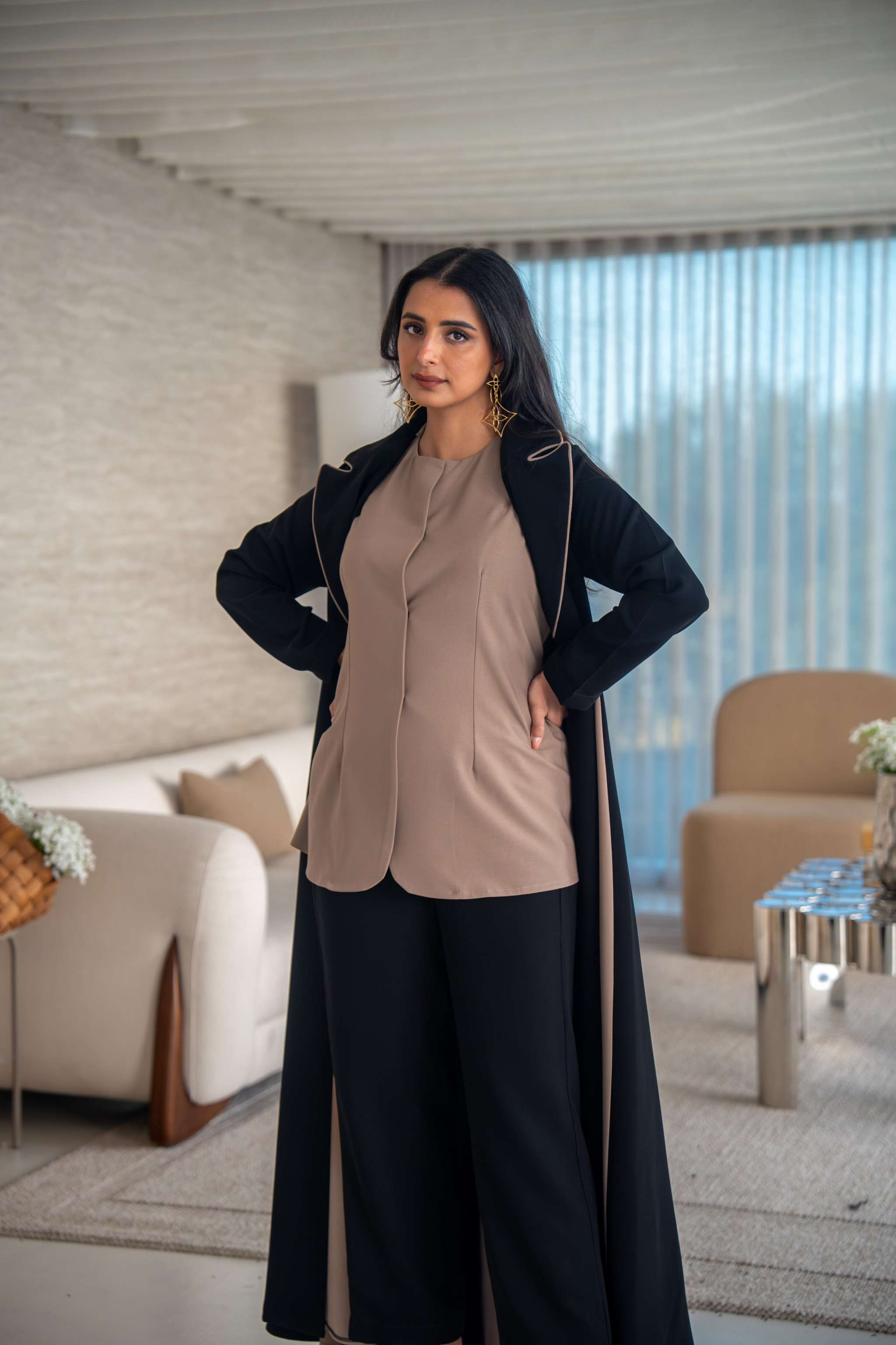Woman wearing elegant black and beige crepe abaya standing in modern living room