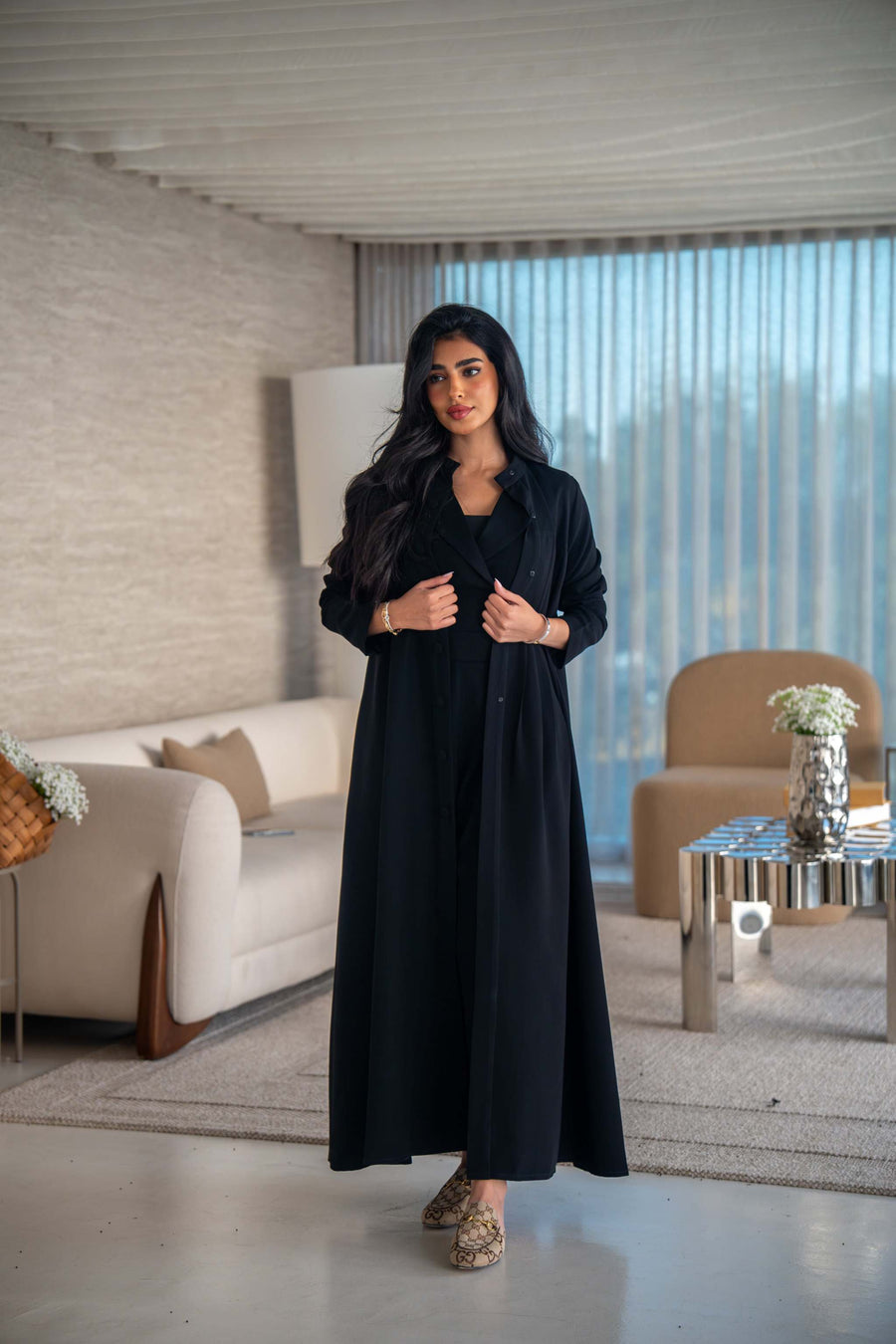 Elegant black crepe abaya with soft, flowing silhouette worn by woman indoors