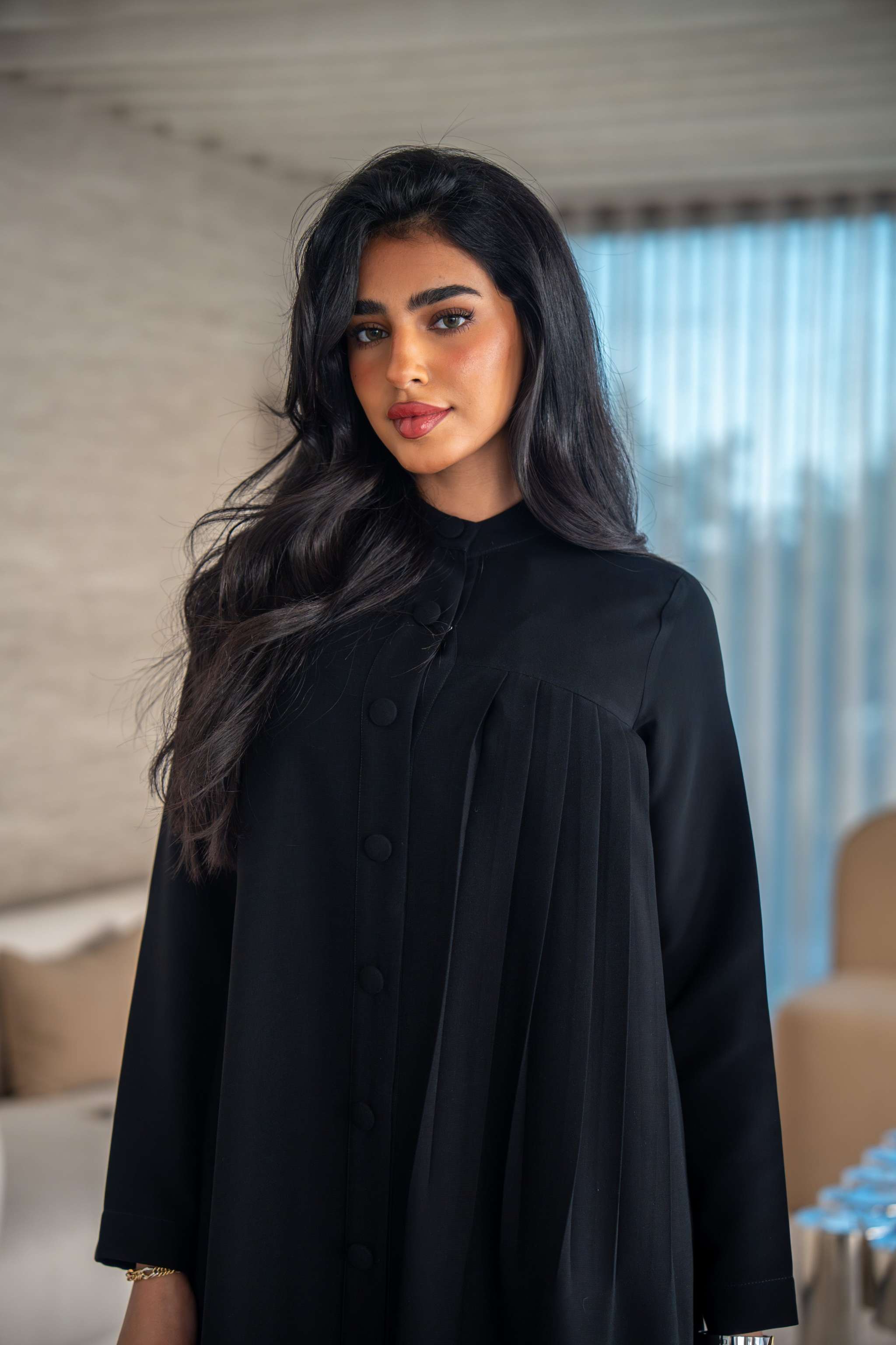 Elegant black crepe abaya with soft, flowing silhouette worn by woman indoors