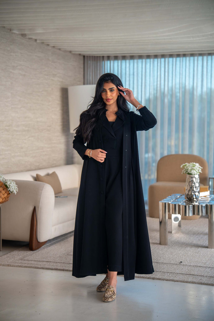 Elegant black crepe abaya with soft, flowing silhouette worn by woman indoors