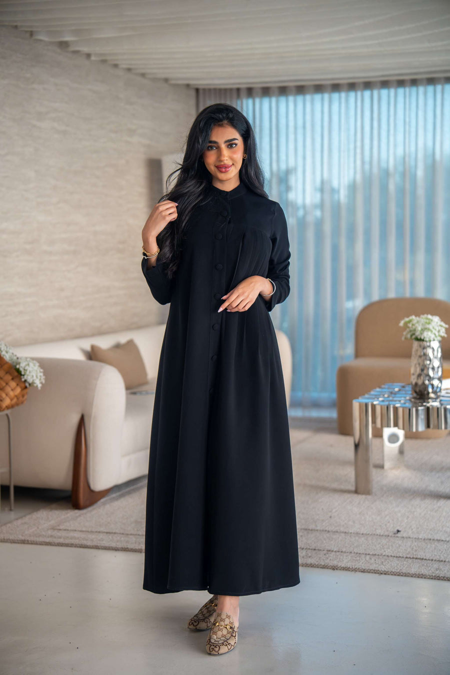 Elegant black crepe abaya with soft, flowing silhouette worn by woman indoors